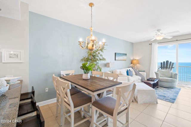 tiled dining room featuring ceiling fan with notable chandelier and a water view