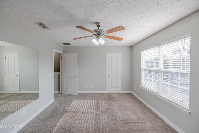 unfurnished room featuring ceiling fan, carpet floors, and a textured ceiling