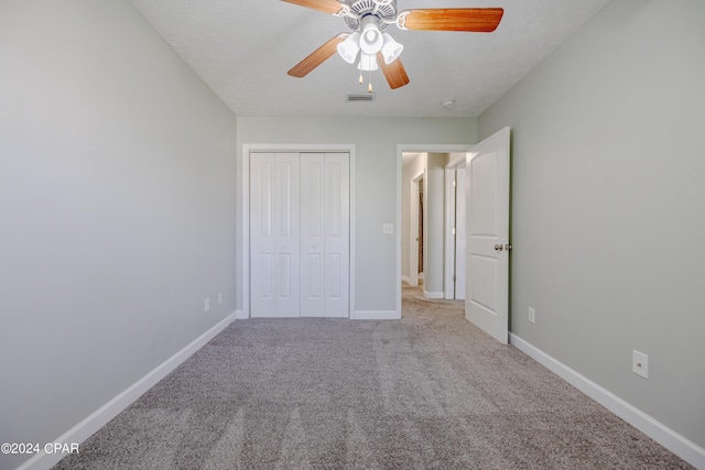 unfurnished bedroom with ceiling fan, a closet, carpet floors, and a textured ceiling