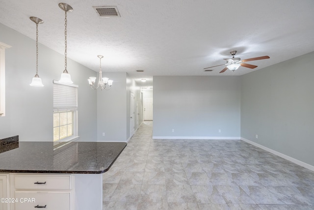 unfurnished living room with a textured ceiling and ceiling fan with notable chandelier