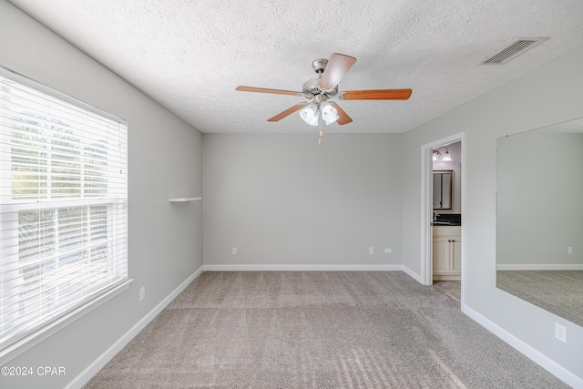 carpeted spare room with a textured ceiling and ceiling fan