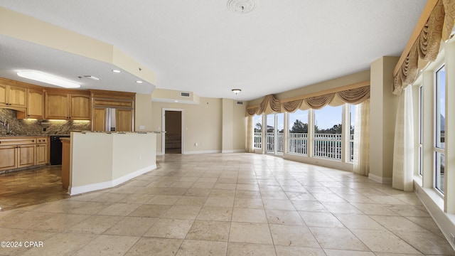 kitchen with decorative backsplash, paneled built in fridge, sink, dark stone countertops, and dishwasher