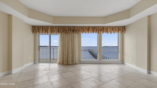 spare room featuring light tile patterned floors, a water view, and plenty of natural light