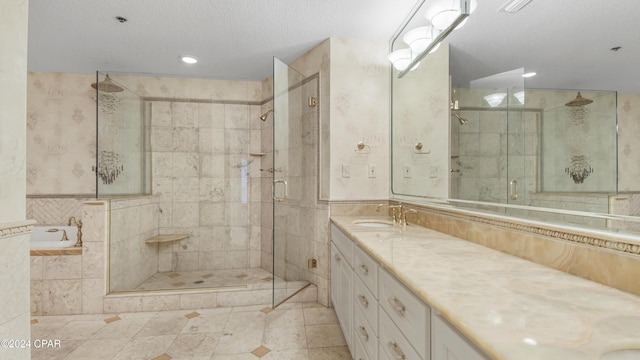 bathroom with a textured ceiling, vanity, separate shower and tub, tile walls, and tile patterned flooring