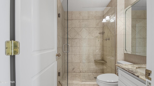 bathroom with vanity, toilet, a shower with shower door, and a textured ceiling