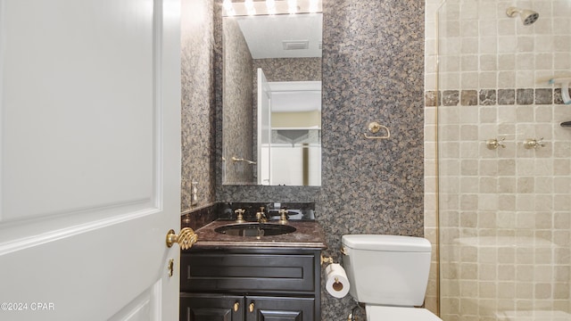 bathroom featuring tiled shower, vanity, and toilet