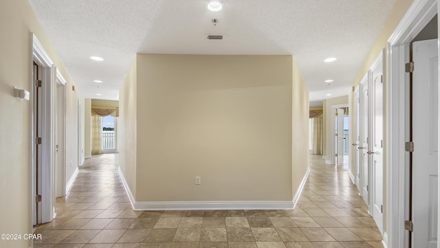 hallway with light tile patterned flooring and a textured ceiling