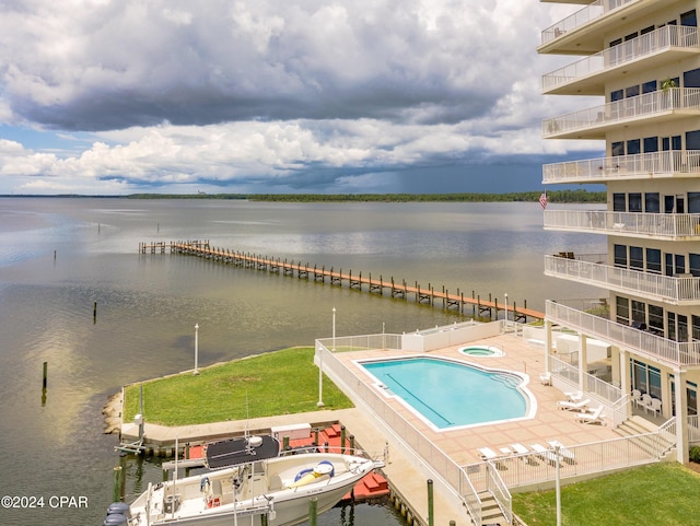 view of swimming pool with a boat dock, a water view, and a patio area