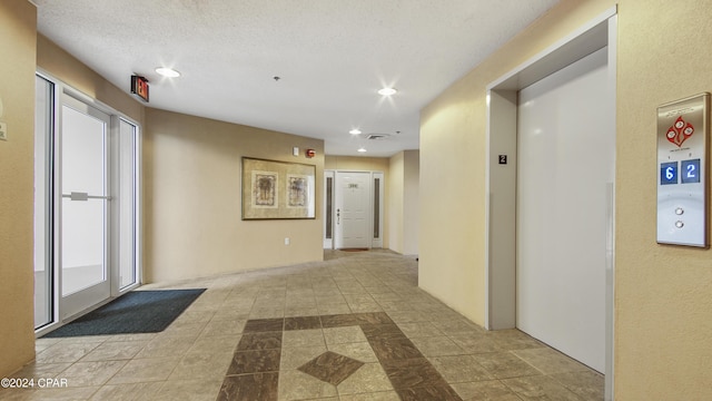 corridor with a textured ceiling and elevator