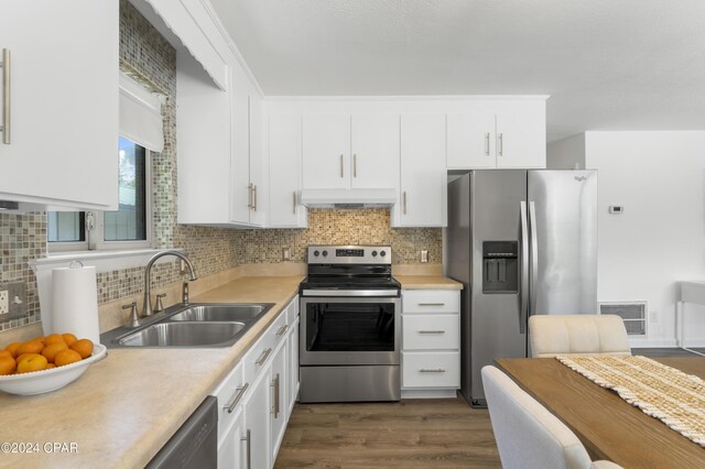 kitchen featuring decorative backsplash, sink, white cabinetry, appliances with stainless steel finishes, and dark hardwood / wood-style flooring