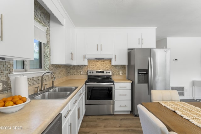 kitchen with appliances with stainless steel finishes, a sink, light countertops, under cabinet range hood, and visible vents
