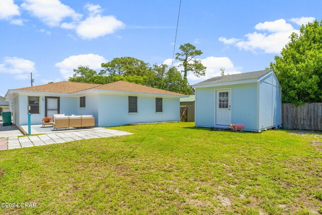 rear view of house featuring a lawn, a shed, an outdoor living space, and a patio