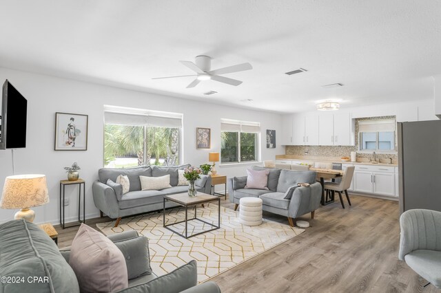 living room featuring ceiling fan, light wood-type flooring, and sink