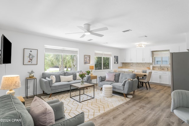 living room featuring light wood-type flooring, visible vents, and a ceiling fan