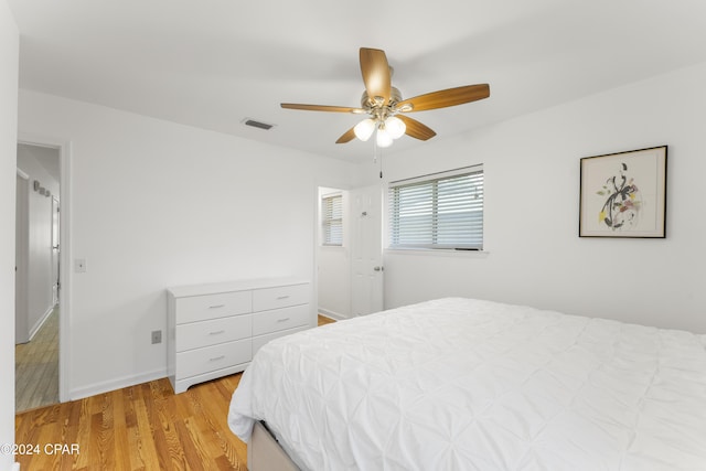 bedroom featuring baseboards, a ceiling fan, light wood finished floors, and visible vents