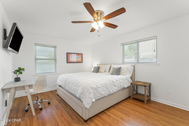 bedroom featuring ceiling fan, multiple windows, and hardwood / wood-style floors