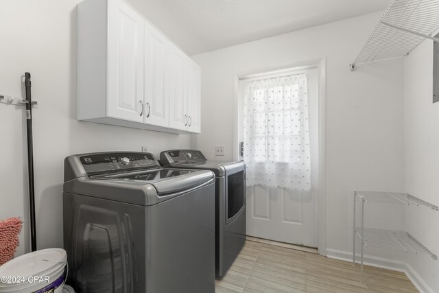 laundry room featuring light tile patterned floors, independent washer and dryer, and cabinets