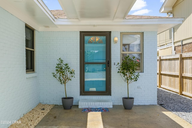doorway to property with brick siding and fence