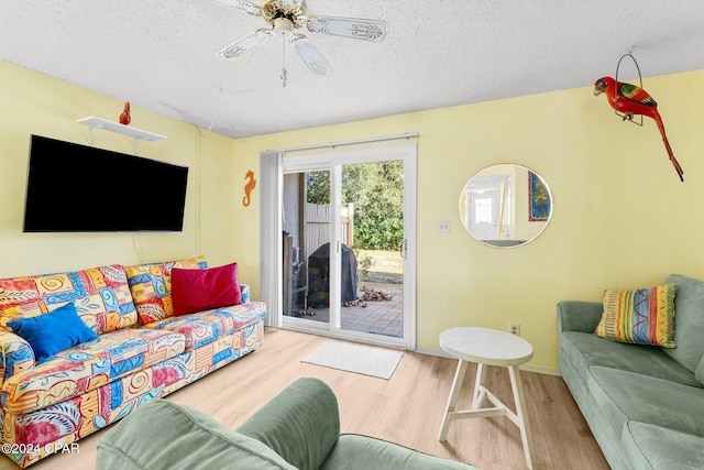 living room with a textured ceiling, light hardwood / wood-style floors, and ceiling fan