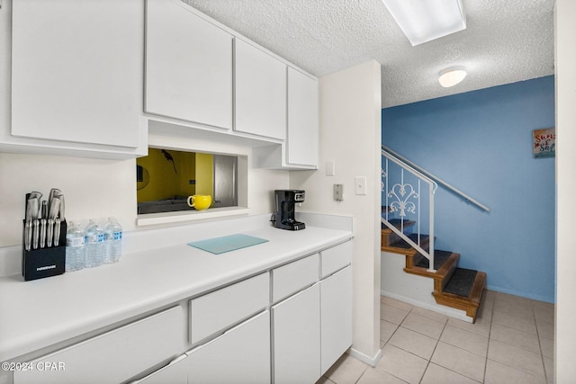 kitchen featuring white cabinetry, light tile patterned flooring, and a textured ceiling