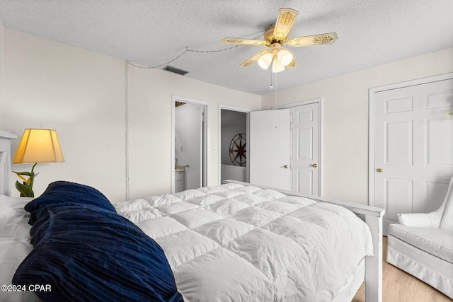 bedroom featuring hardwood / wood-style floors, a textured ceiling, ensuite bathroom, and ceiling fan