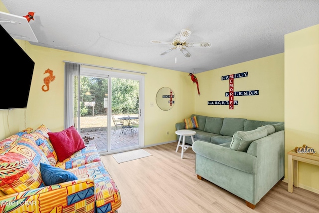 living room with ceiling fan, a textured ceiling, and light wood-type flooring