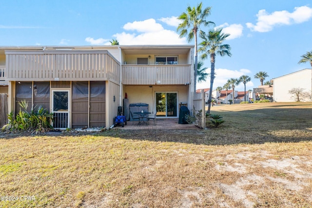 rear view of property with a lawn, a balcony, and a patio