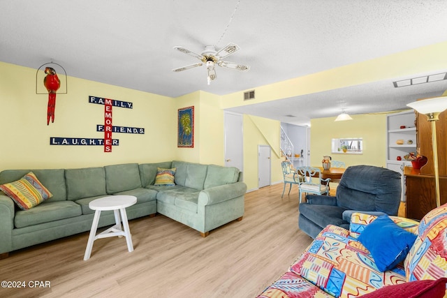 living room featuring ceiling fan, a textured ceiling, and light hardwood / wood-style flooring