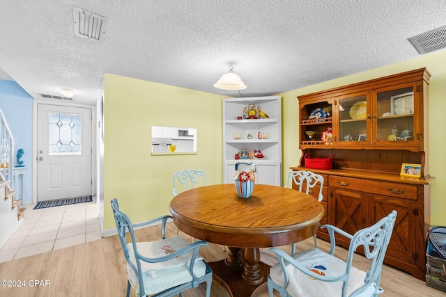 dining area with light hardwood / wood-style floors and a textured ceiling