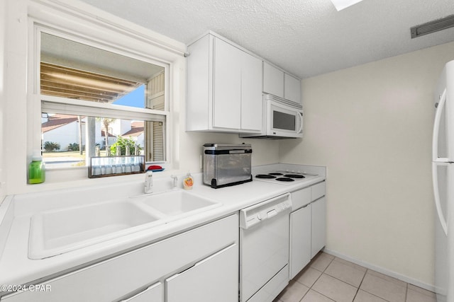 kitchen featuring a textured ceiling, white appliances, white cabinetry, and light tile patterned flooring