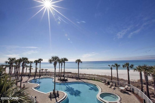 view of pool with a community hot tub, a water view, and a beach view