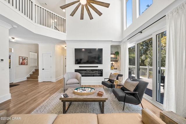 living room featuring a high ceiling, ceiling fan, a wealth of natural light, and wood-type flooring