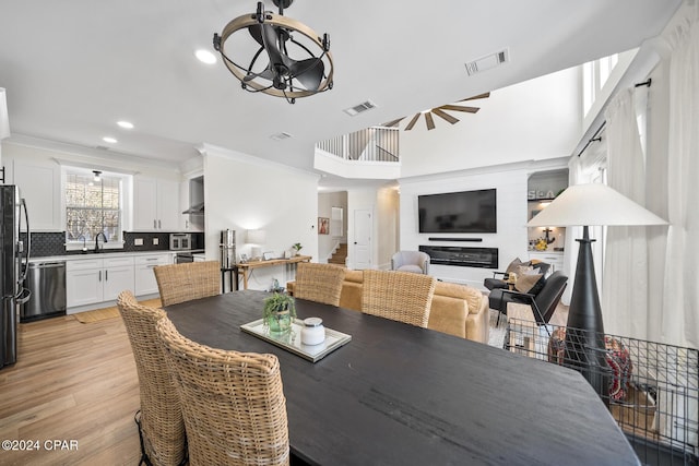 dining area featuring light hardwood / wood-style floors, a notable chandelier, crown molding, and sink