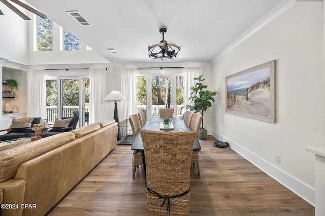 dining space with wood-type flooring, a healthy amount of sunlight, and an inviting chandelier