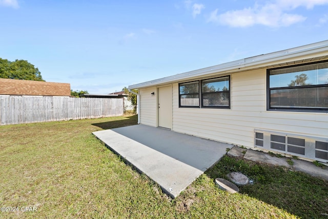 view of exterior entry with a yard and a patio