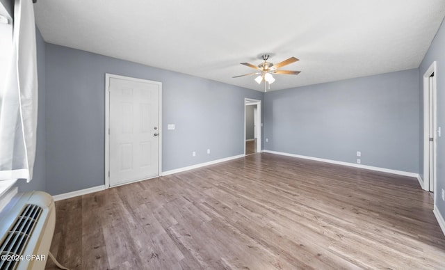 unfurnished room with light wood-type flooring, a wall mounted AC, and ceiling fan