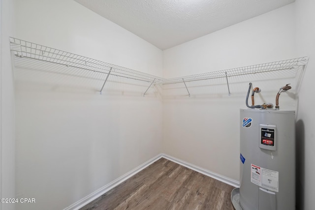 walk in closet with electric water heater and hardwood / wood-style floors