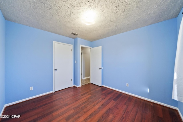 unfurnished bedroom featuring a textured ceiling and dark hardwood / wood-style floors