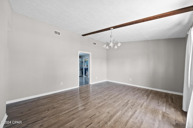 spare room with hardwood / wood-style floors, a textured ceiling, and an inviting chandelier