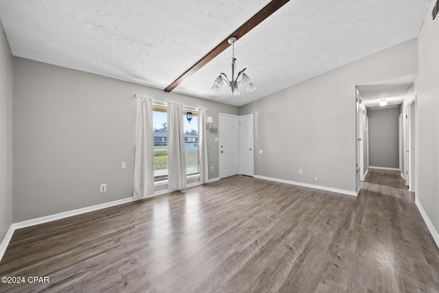 spare room with vaulted ceiling with beams, dark hardwood / wood-style flooring, a textured ceiling, and a chandelier