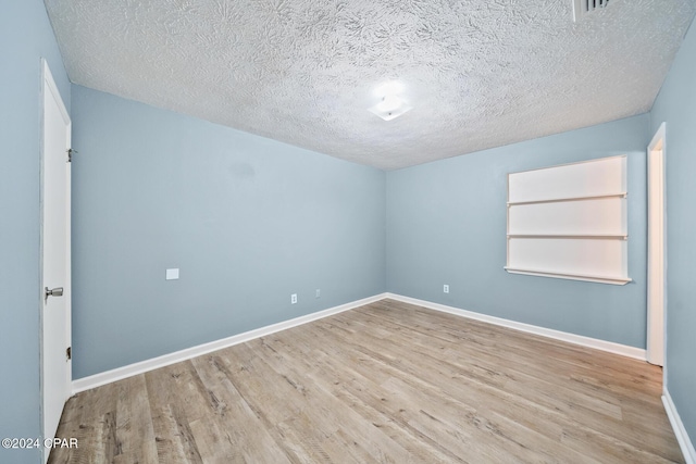 spare room with light hardwood / wood-style floors and a textured ceiling