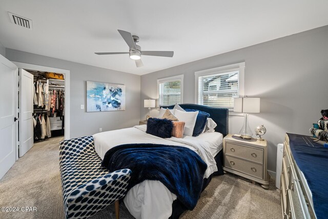 bedroom featuring a closet, light colored carpet, visible vents, a spacious closet, and ceiling fan