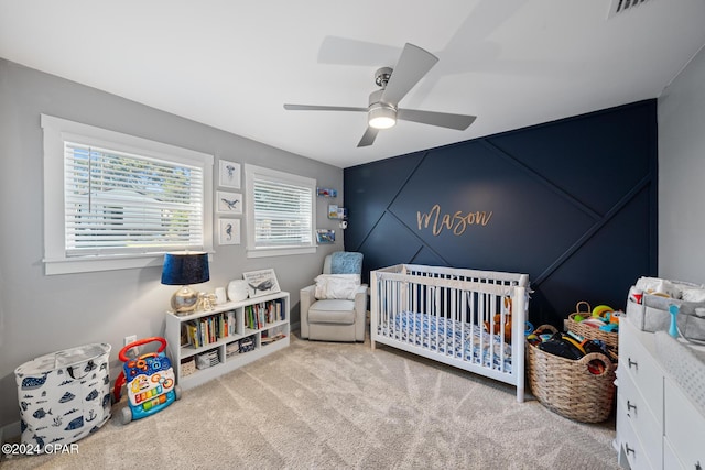 bedroom featuring a ceiling fan, a nursery area, carpet flooring, and visible vents