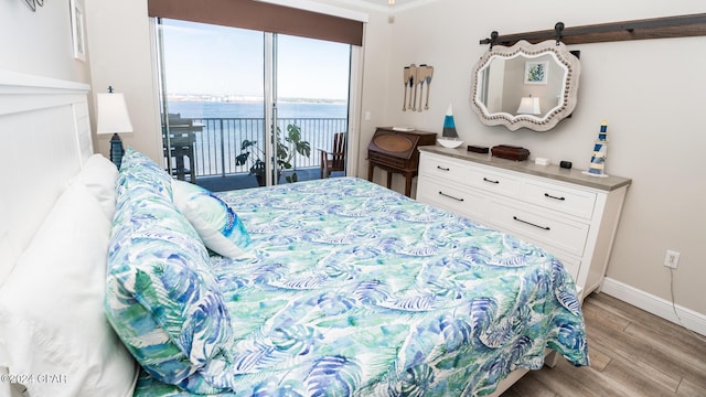 bedroom featuring access to exterior, ornamental molding, a water view, and light hardwood / wood-style flooring