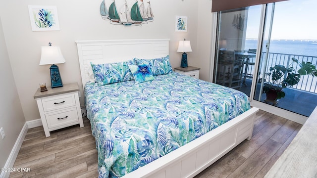 bedroom with access to outside, a water view, and wood-type flooring