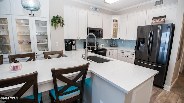 kitchen with kitchen peninsula, a breakfast bar, white cabinets, and stainless steel appliances