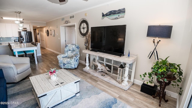 living room featuring ceiling fan, light hardwood / wood-style floors, and ornamental molding