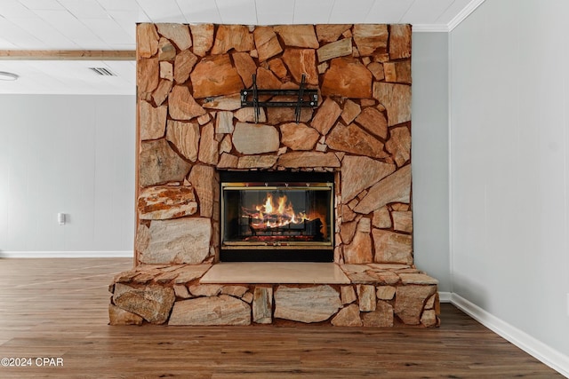 details with hardwood / wood-style floors, a stone fireplace, and ornamental molding