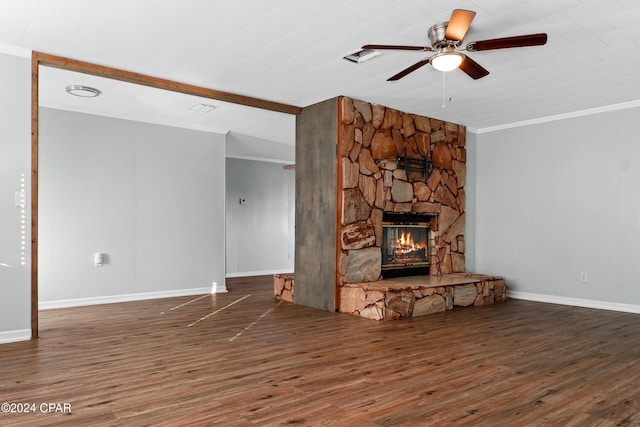 unfurnished living room with dark hardwood / wood-style flooring, a stone fireplace, ceiling fan, and ornamental molding