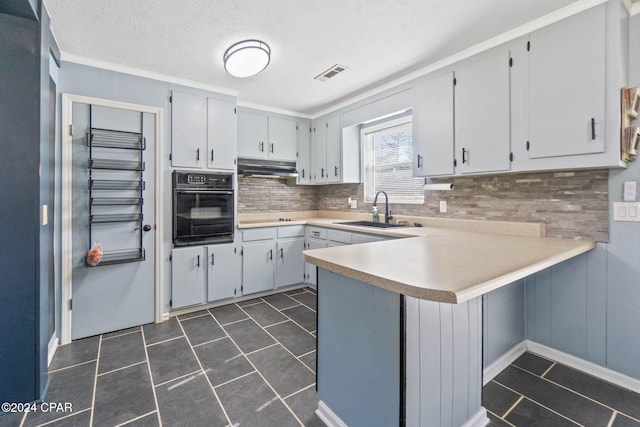 kitchen featuring kitchen peninsula, backsplash, a textured ceiling, sink, and oven